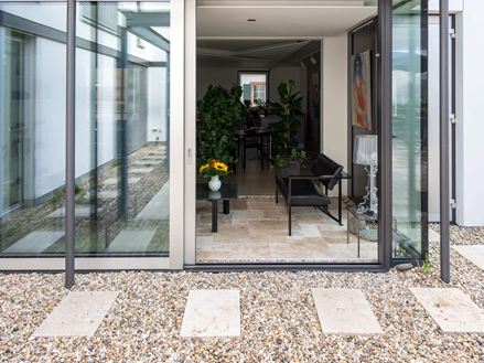 Vue sur le jardin d'hiver depuis la terrasse en dalles de travertin Rustic