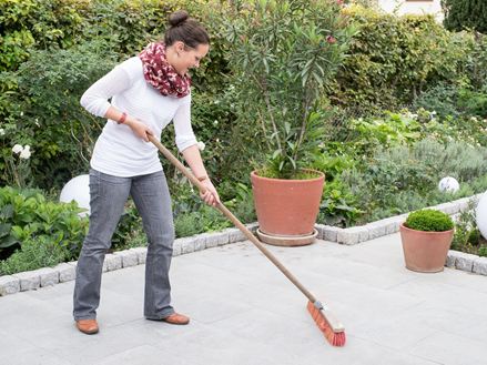 Une femme nettoie sa terrasse en granite gris Mundo 