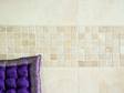 Frise en mosaïque de travertin au mur et coussin violet dans le coin