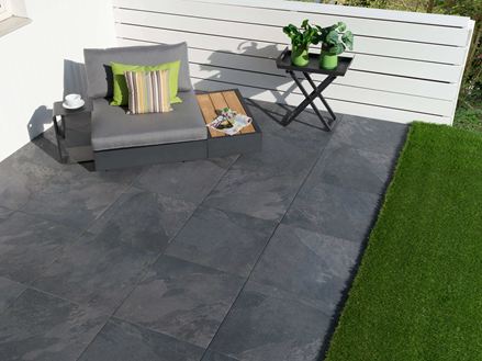 Un sofa d'extérieur sur une terrasse au dallage en grès cérame imitation ardoise Alpine Black