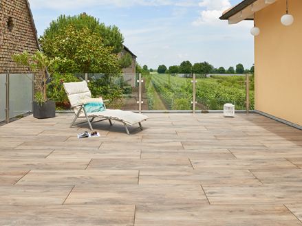 Terrasse avec dalles imitation parquet, vignobles en arrière-plan et chaise longue