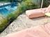 Terrasse en travertin Medium Select autour de la piscine, plants de lavande et sièges de jardin roses