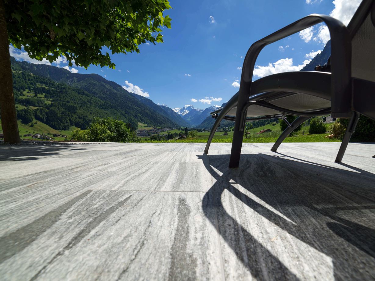 Terrasse avec dalles de granit Urban Grey Line et chaise longue avec vue sur les Alpes