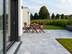 Terrasse en marbre Afyon Grey dans une teinte gris clair. Table et chaises de jardin en bois en arrière-plan.
