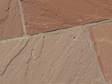 Gros plan sur les dalles en grès Modak aux tons rouges et beiges posées sur une terrasse