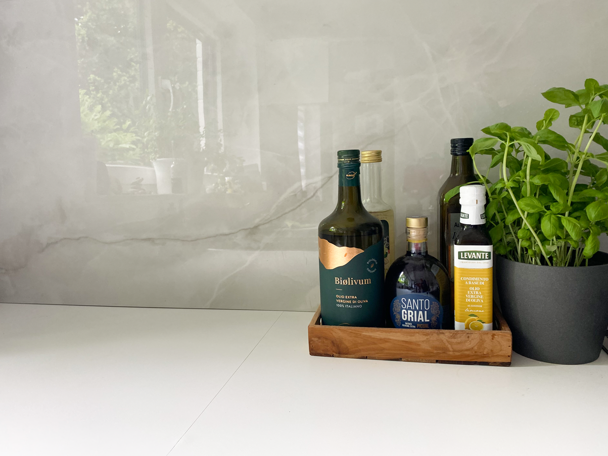 Carrelage imitation marbre Perla Crema en crédence avec huiles et basilic