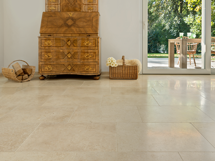 Armoire ancienne en bois sur carrelage clair en pierre calcaire Cleopatra Light, et vue sur la terrasse et le jardin