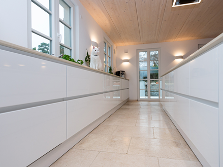 Une cuisine ouverte avec un mobilier blanc et un carrelage en pierre calcaire Cleopatra Light