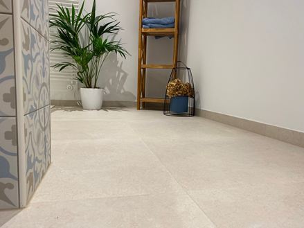 Salle de bain moderne avec meubles en bois, plante décorative et carrelage clair imitation pierre calcaire