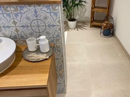 Salle de bains avec éléments en bois et plante décorative, carrelage imitation pierre calcaire Sevilla Cream comme revêtement de sol