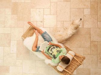 Garçon lit dans une chaise longue sur des carreaux de travertin clairs en opus romain