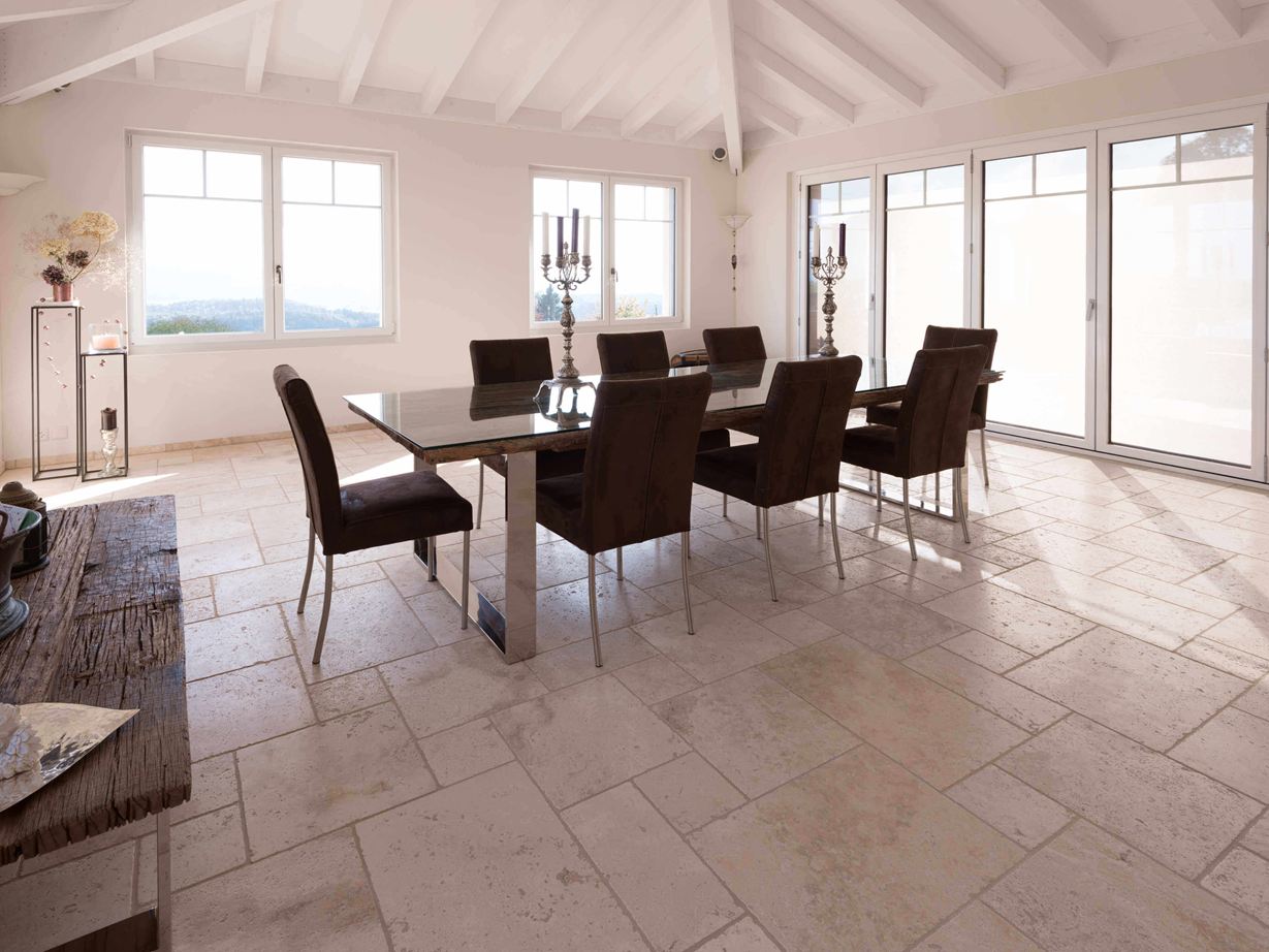 Salle à manger avec table et chaises et au sol un carrelage en travertin Light en format opus romain