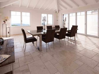 Salle à manger avec table et chaises et au sol un carrelage en travertin Light en format opus romain