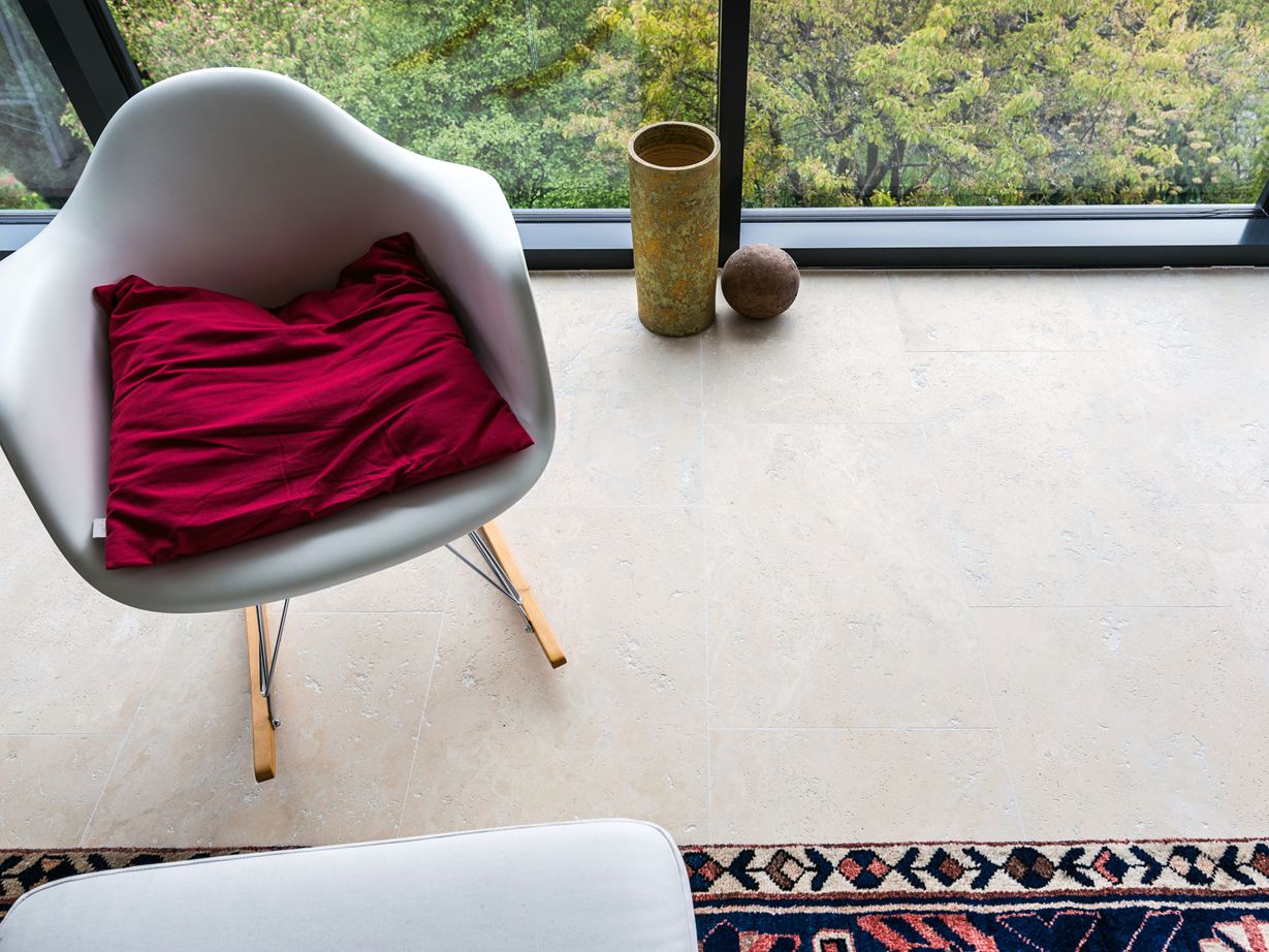 Des tons beiges chauds et intenses sous un éclairage indirect Couloir avec mur en pierre naturelle, buffet en bois et carreau de travertin beige Medium Line comme revêtement de sol