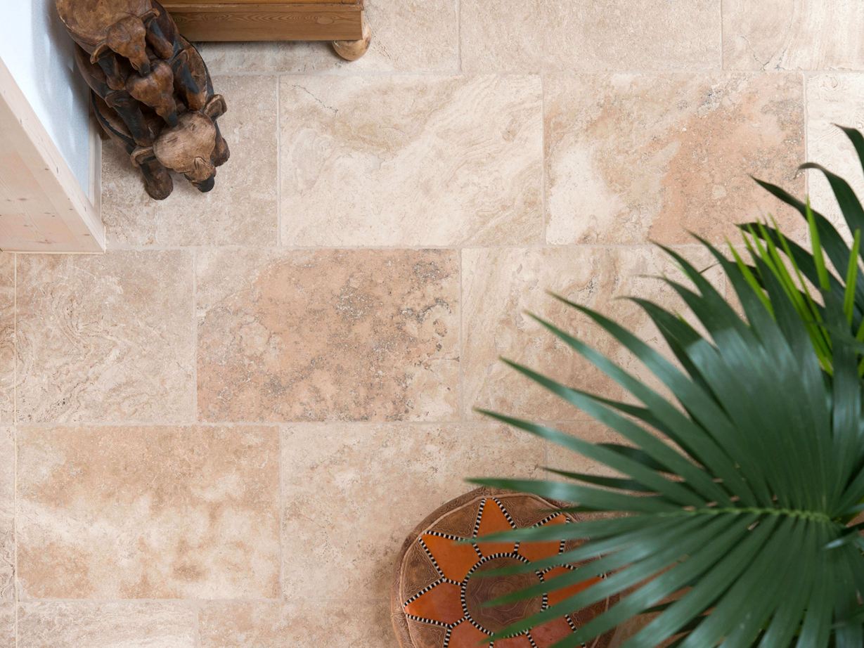Vue de haut sur les carreaux en travertin Rustic, avec mobilier en bois, pouf et palmier