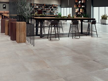 Un carrelage effet béton Pure Clay accompagné d'une table et de chaises.