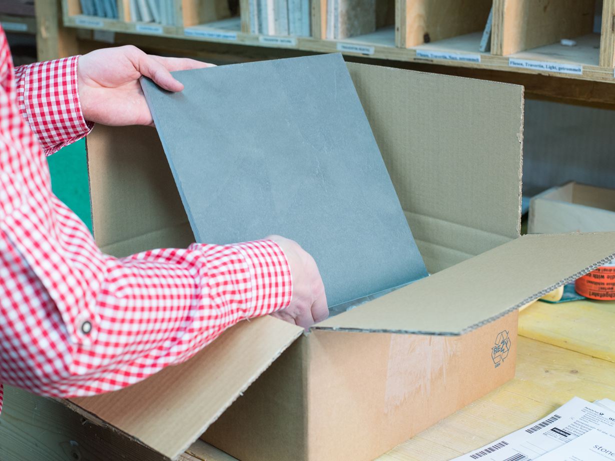 Un employé emballe une planche d'échantillonnage en pierre dans une boîte en carton.