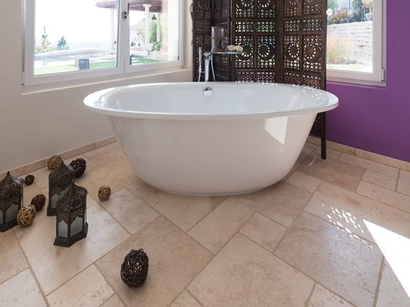 Une baignoire avec des accessoires orientaux sur le sol en travertin Light (tambouriné)