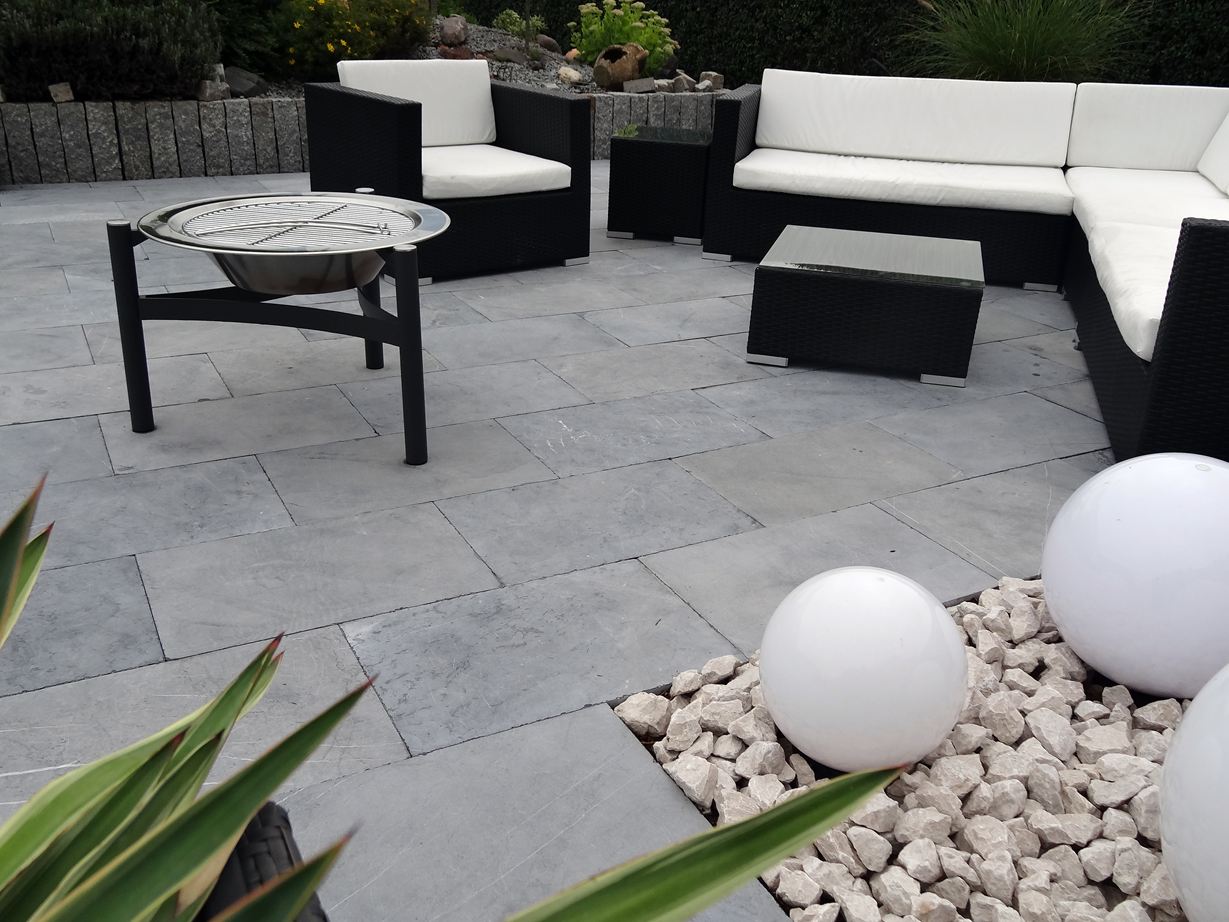 Des meubles de jardin modernes en blanc et noir sur la pierre calcaire Blaustein Azur avec un doux reflet en bleu.