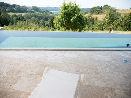 premier plan transat blanc et derrière grande piscine