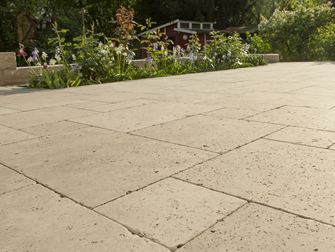 Dalle Medium SELECT, en travertin avec un massif de fleurs en arrière plan