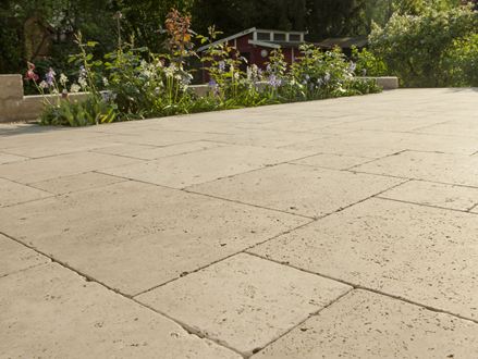Dalle Medium SELECT, en travertin avec un massif de fleurs en arrière plan