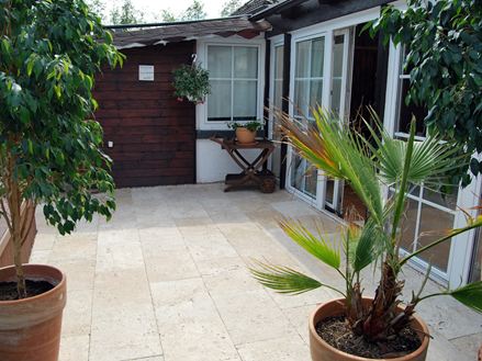 Une cabane de jardin à côté de l'accès à la maison et sol beige clair en travertin Medium