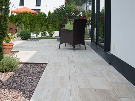 Terrasse moderne avec dalles de travertin Natura en aspect bois et meubles en osier foncé