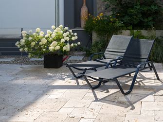 Terrasse en travertin Rustic avec deux chaises longues et un pot de fleurs