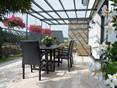 Natura crée un extérieur à la fois moderne et naturel. Terrasse avec meubles de jardin sombres et travertin Natura en bois comme revêtement de sol