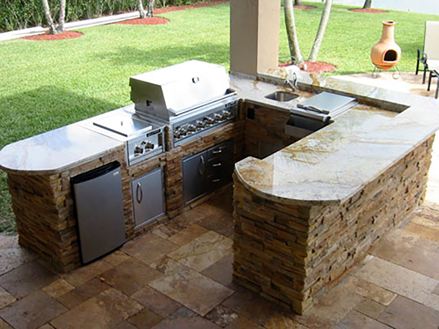 Outdoorküche mit Naturstein und Garten im Hintergrund
