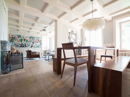 Salon et salle à manger modernes avec de hauts plafonds blancs, plancher en bois et une peinture moderne à l'arrière-plan.