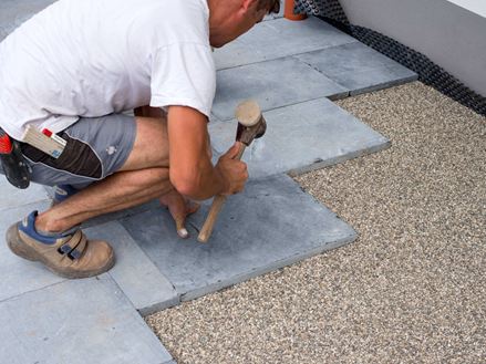 une homme sur la gauche qui pose sur un nid de gravillons la pierre naturelle