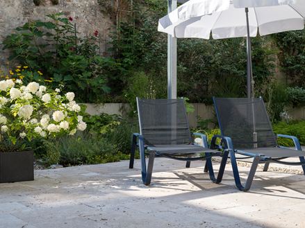 Terrasse ensoleillée avec dalles en travertin et deux chaises longues