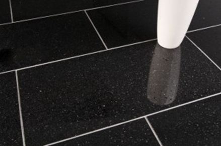 Eine weiße Vase auf schwarzen Granitfliesen mit hellen Fugen