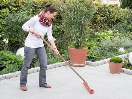 Une femme nettoie une terrasse en granit gris