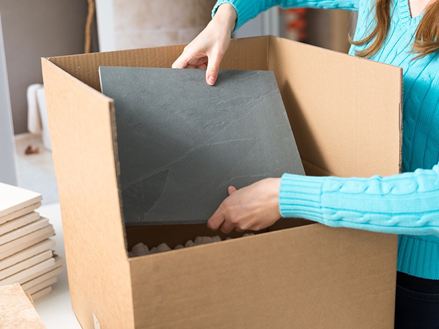 Mitarbeiterin packt ein Natursteinmuster in einen Karton ein