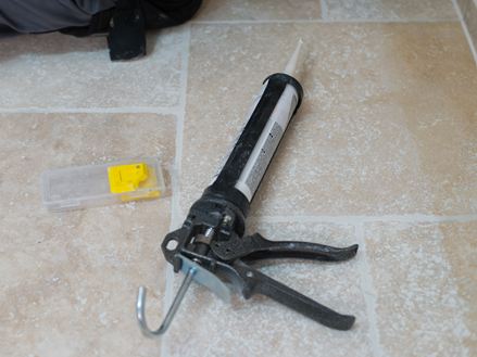 Silikonkartusche und Fugenglätter auf einem Travertinboden