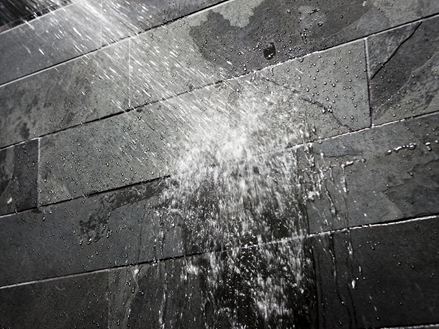 Wasser auf einer dunklen Steinwand im Bad